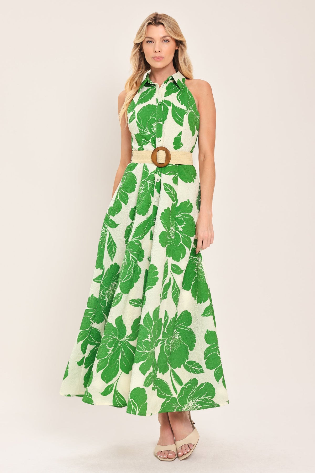 Woman wearing a green floral dress with a belt on a white background