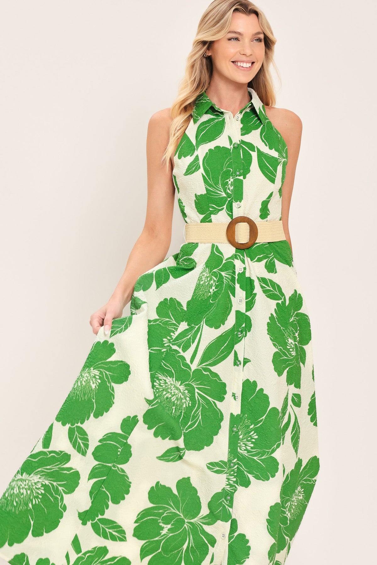 Woman wearing a green floral dress with a belt on a beige background