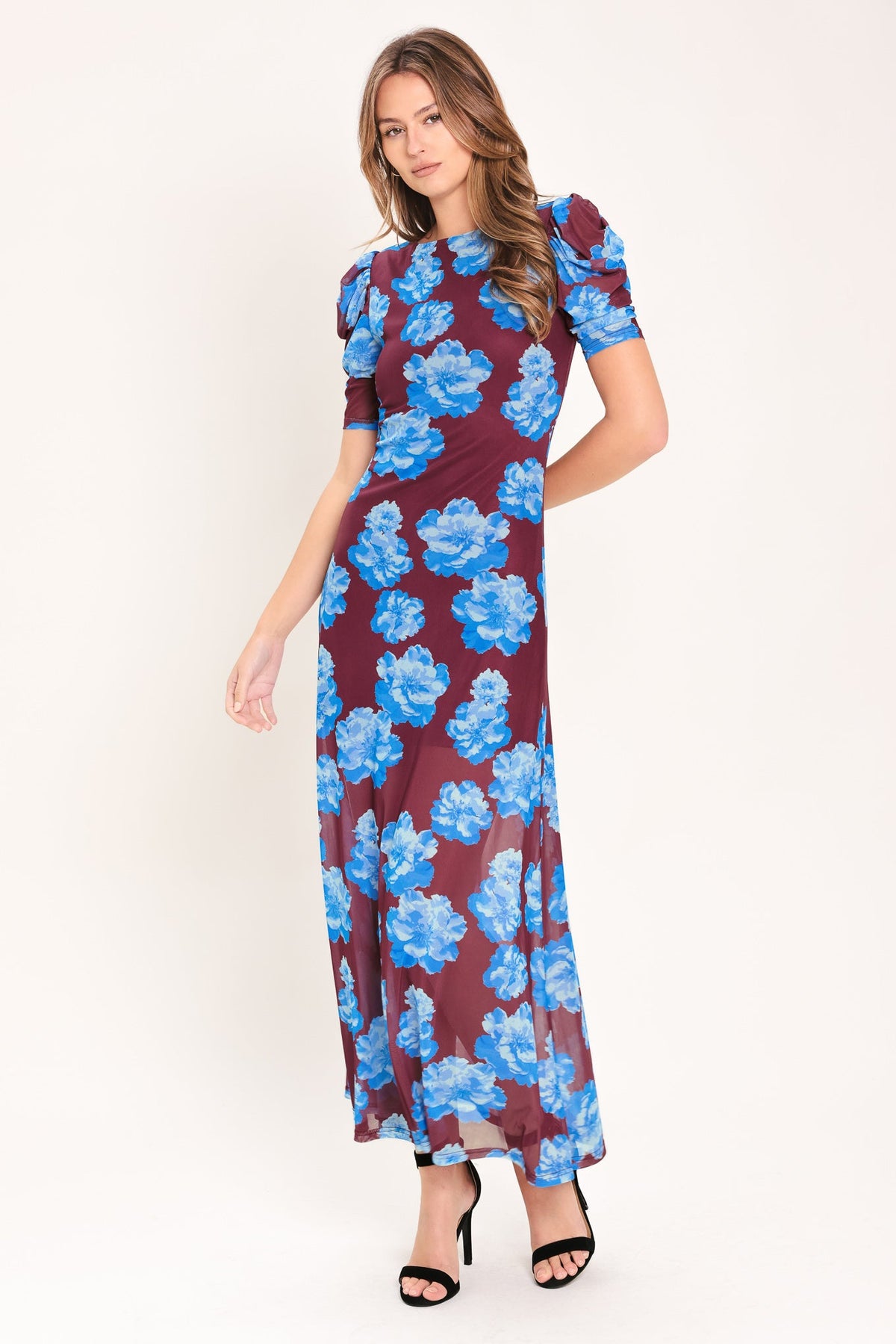 Woman wearing a burgundy dress with blue floral pattern on a white background