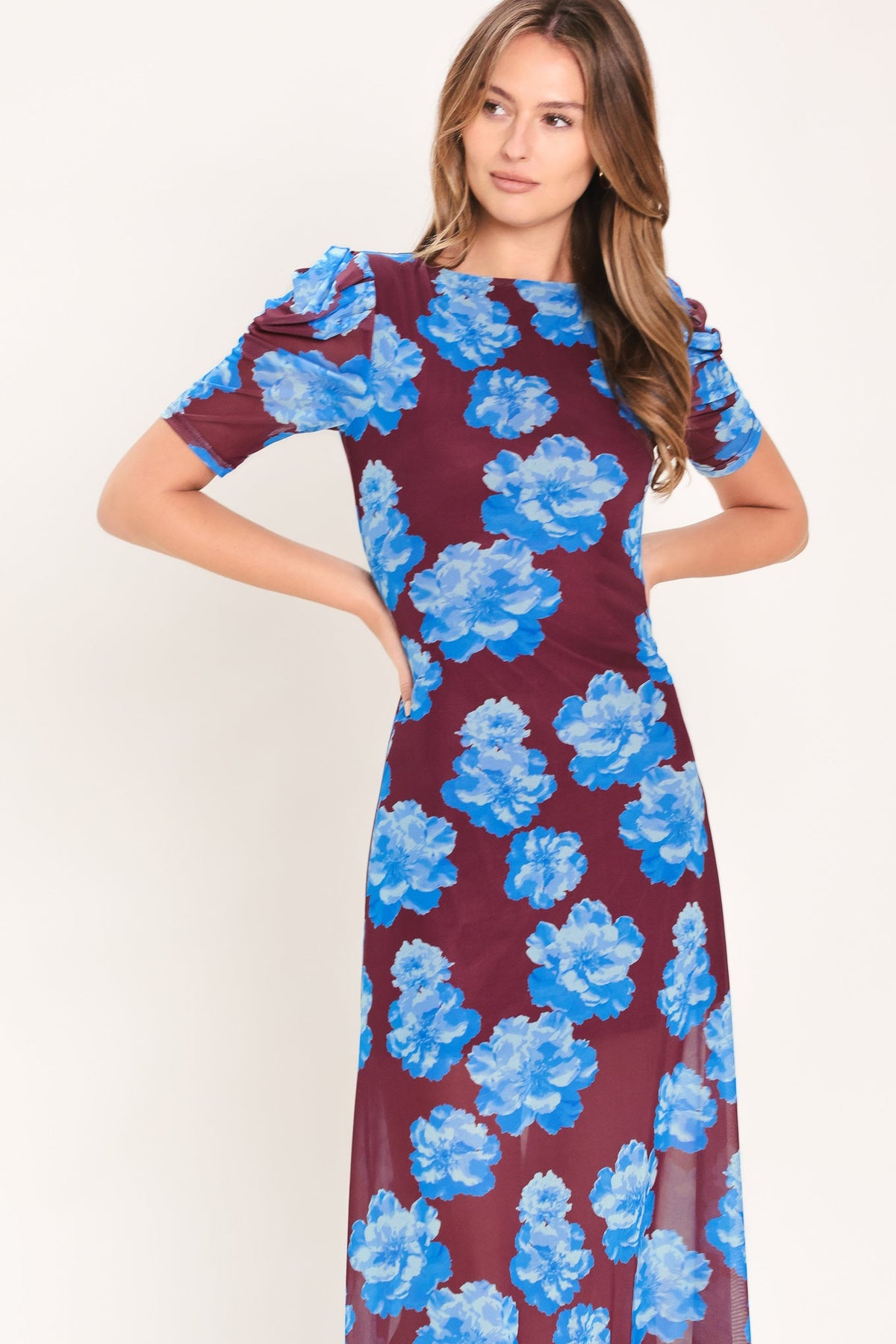 Woman wearing a burgundy dress with blue floral pattern on a white background