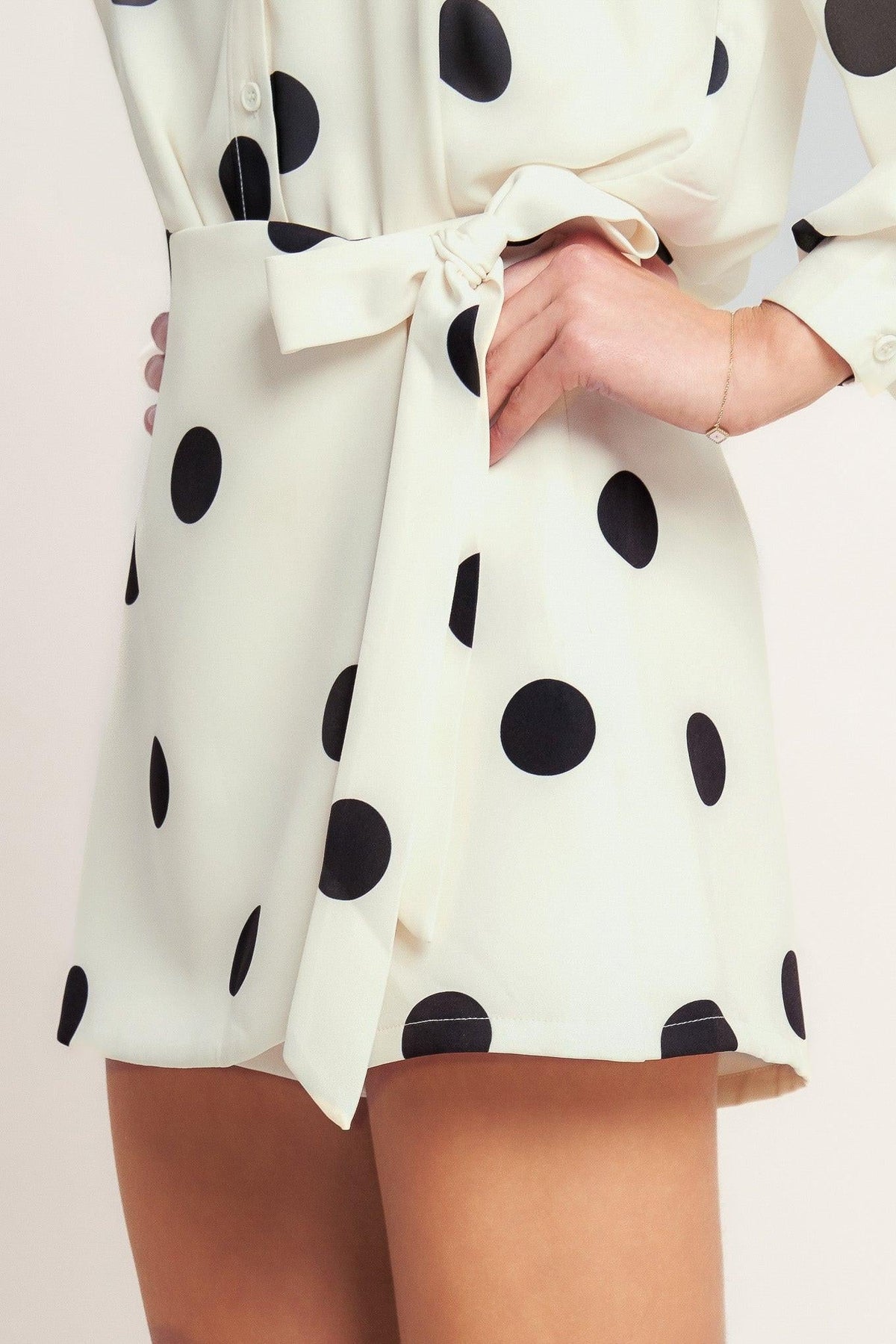 White dress with black polka dots and a tie waist on a light background