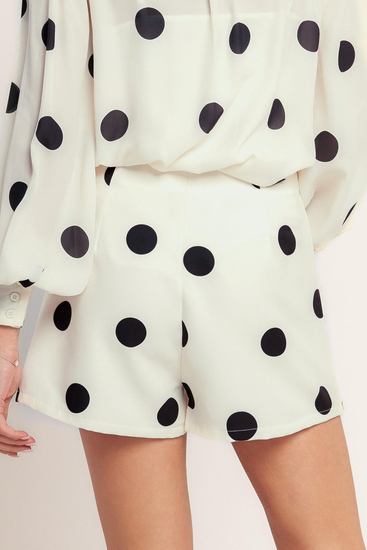 White outfit with black polka dots on a plain background