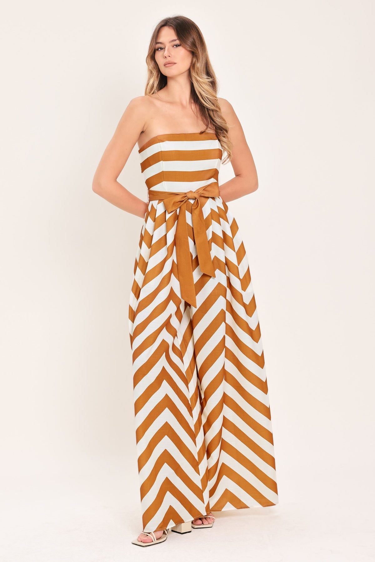 Woman wearing a strapless dress with yellow and white chevron pattern on a white background