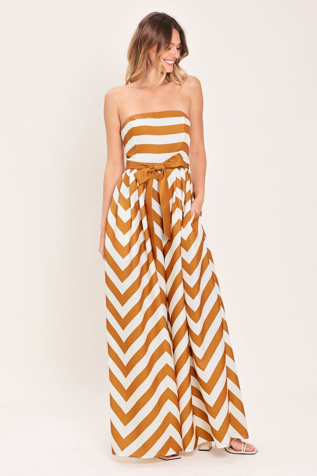 Woman wearing a strapless, chevron-patterned jumpsuit on a white background