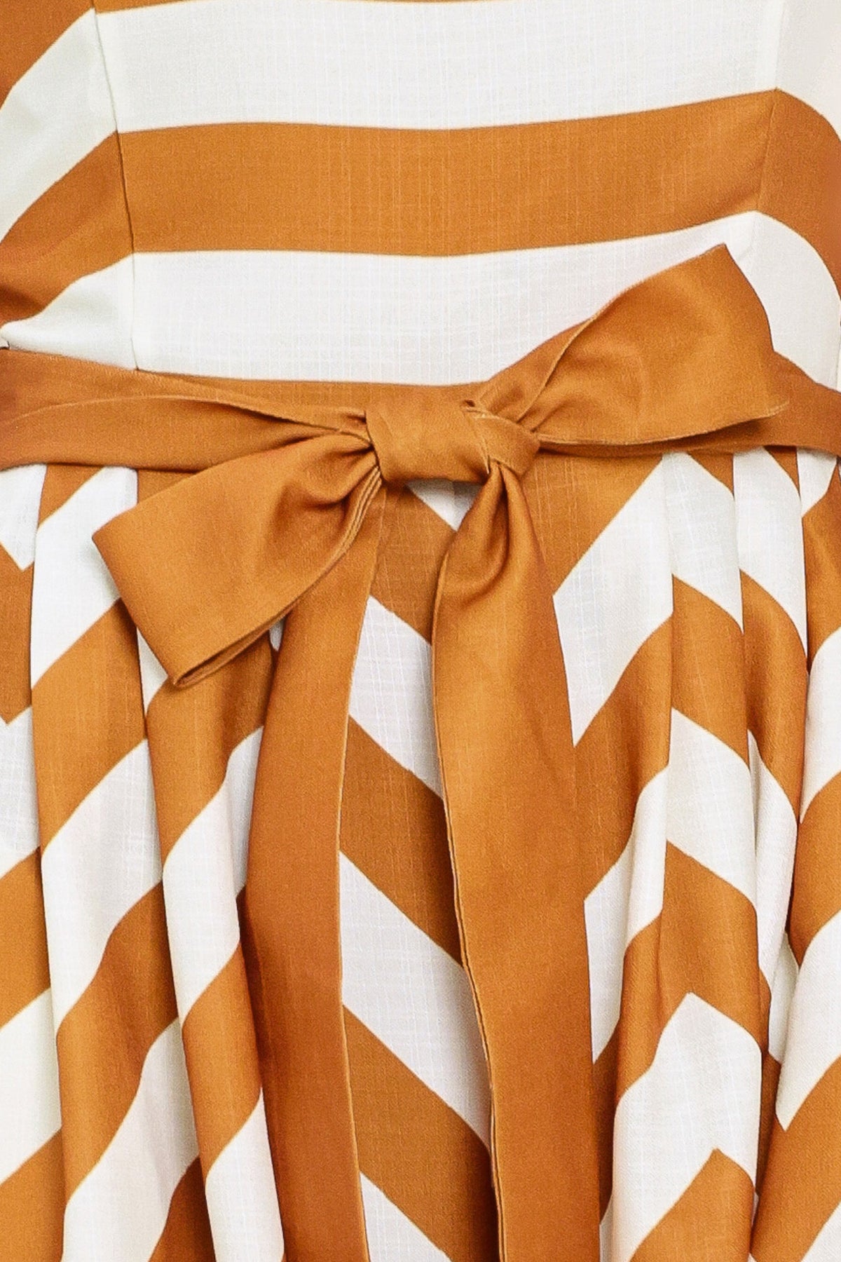 Close-up of a brown and white striped dress with a bow detail.