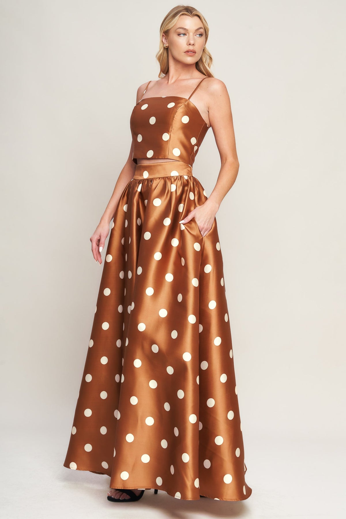 Woman wearing a brown dress with white polka dots on a plain background