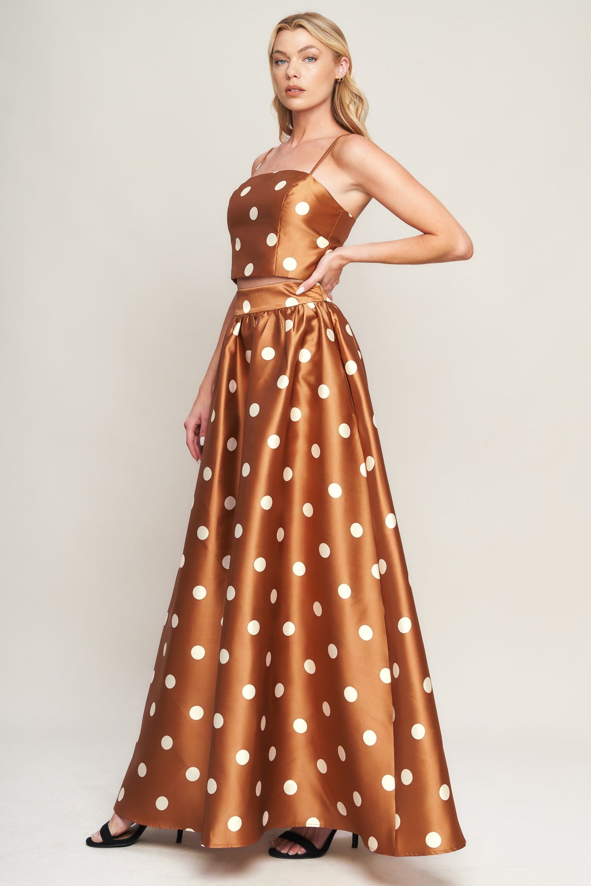 Woman wearing a brown dress with white polka dots on a plain background