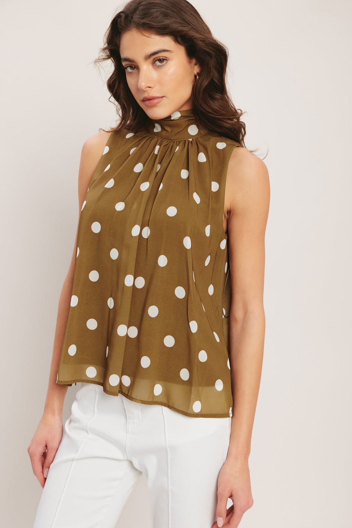 Woman wearing a polka dot blouse with a plain background