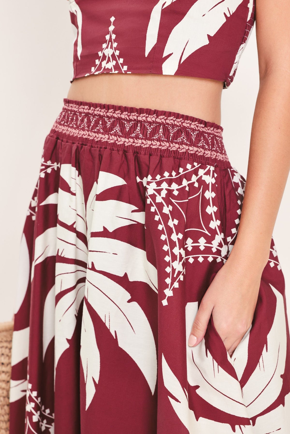 Maroon and white patterned outfit with a top and skirt on a plain background
