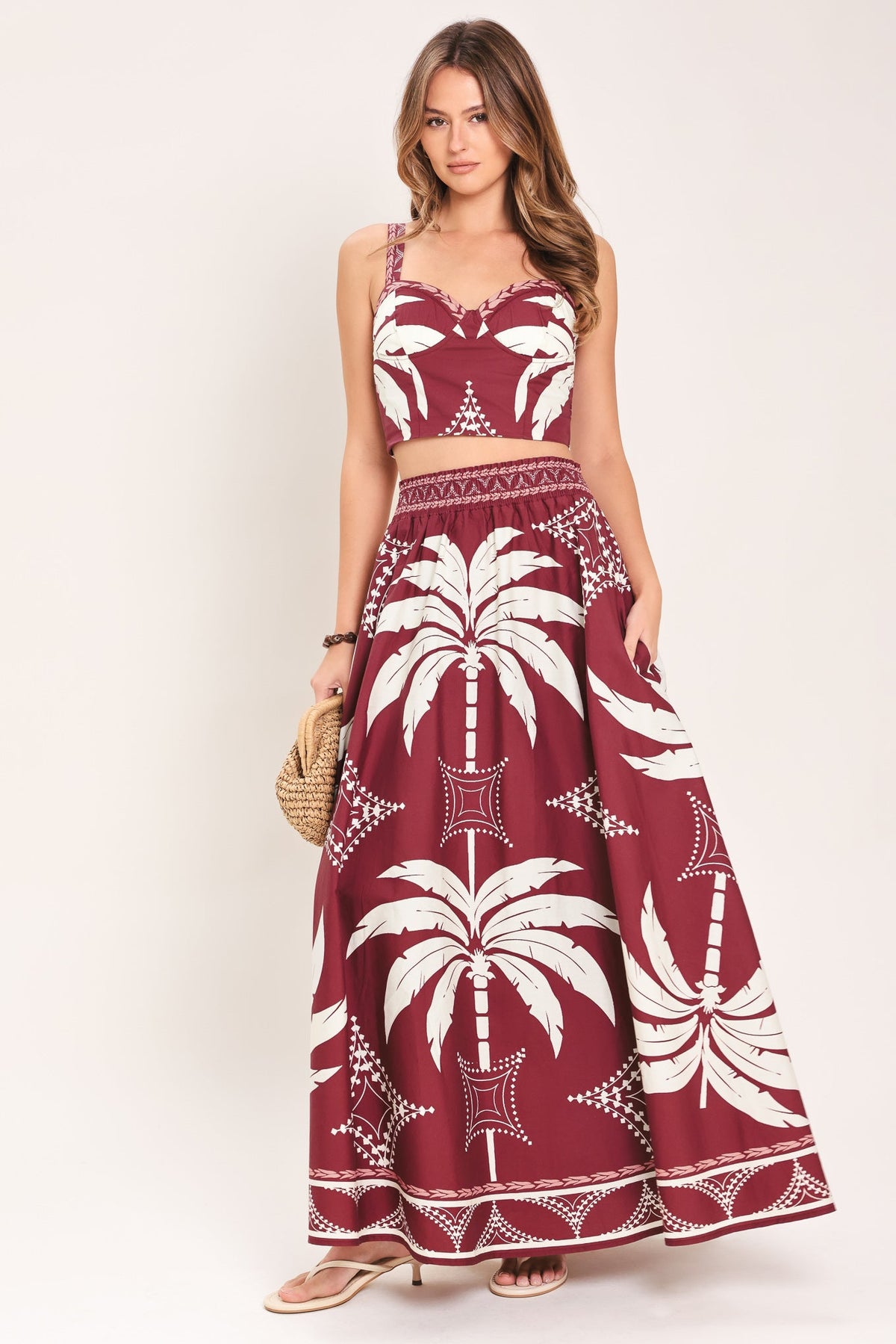 Woman wearing a red and white patterned dress with palm tree design on a plain background