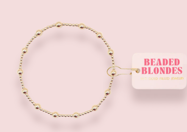 Gold beaded bracelet on a pink background with 'Beaded Blondes' branding.