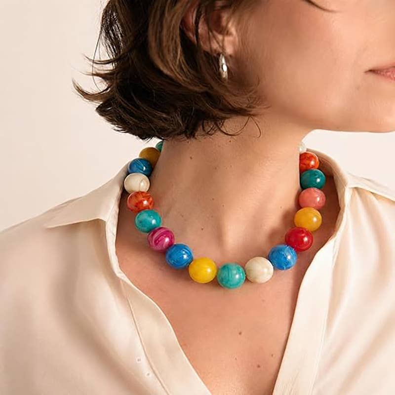 Colorful beaded necklace worn by a person on a plain background