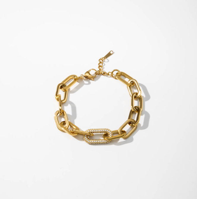 A gold chain link bracelet with a central rectangular link paved with small clear stones, displayed on a clean white background.