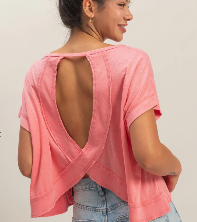 Woman wearing a pink open-back top with a plain background