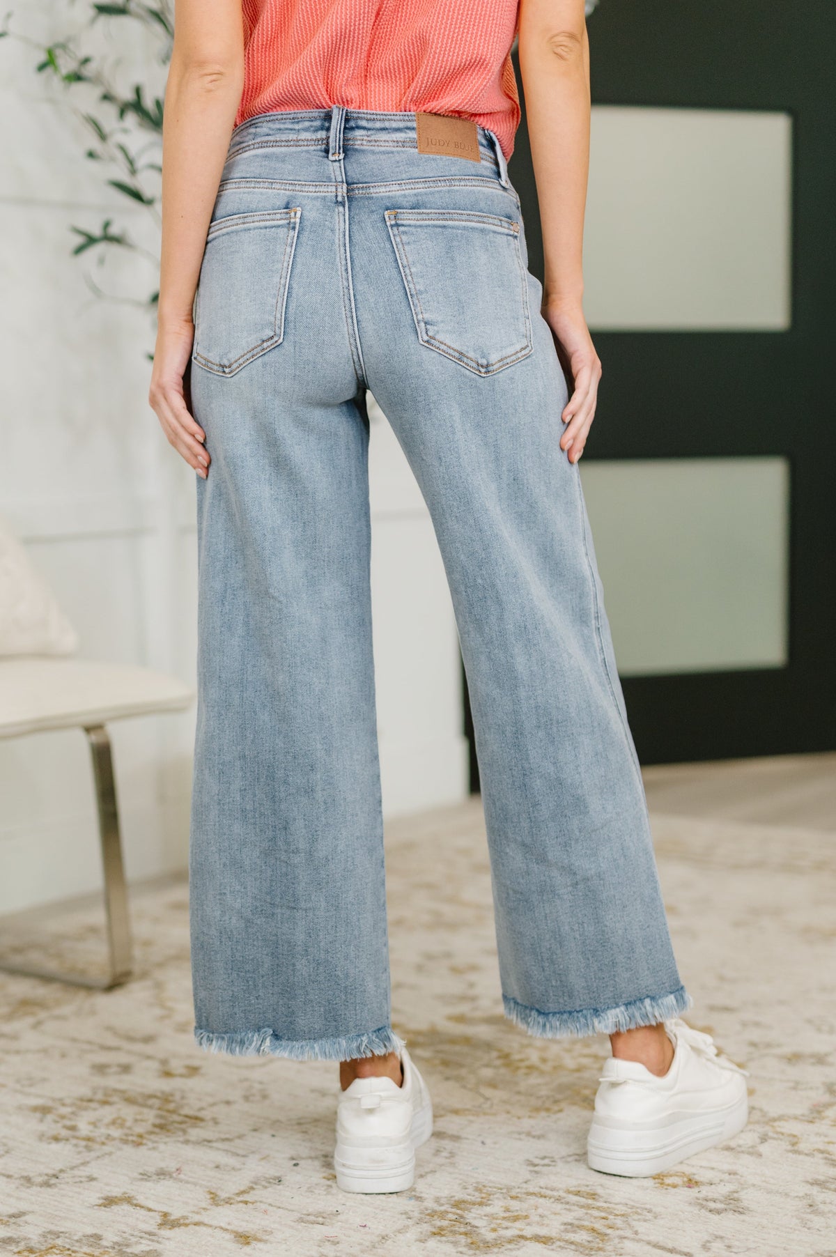 Person wearing light blue jeans and a pink top in an indoor setting