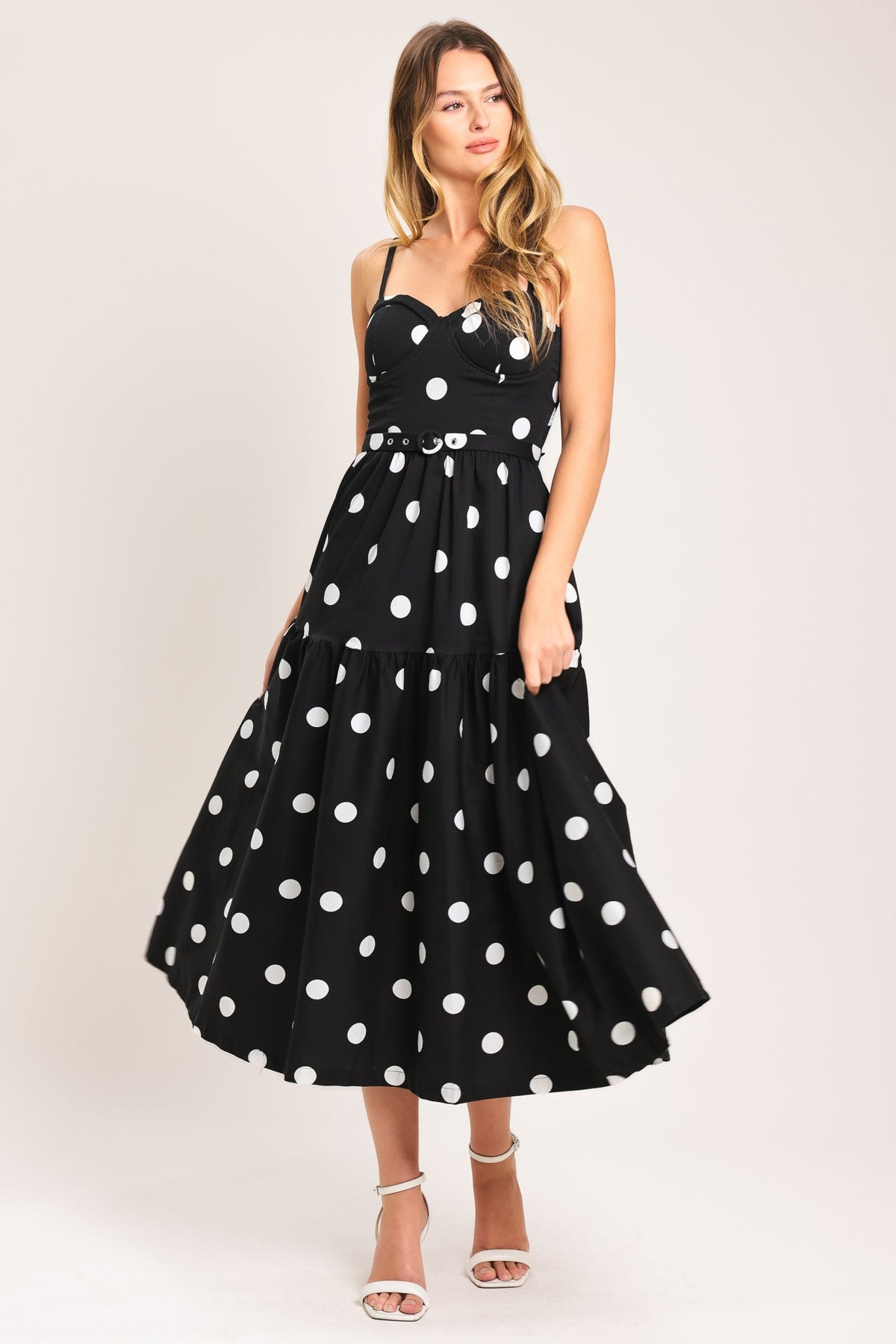 Woman wearing a black dress with white polka dots on a plain background