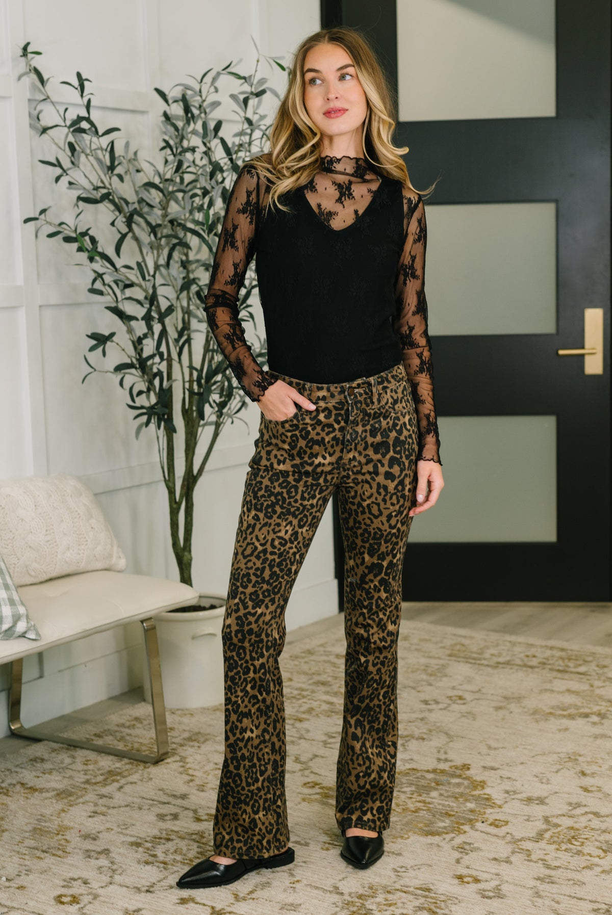 Woman wearing a black top and leopard print pants in an indoor setting.