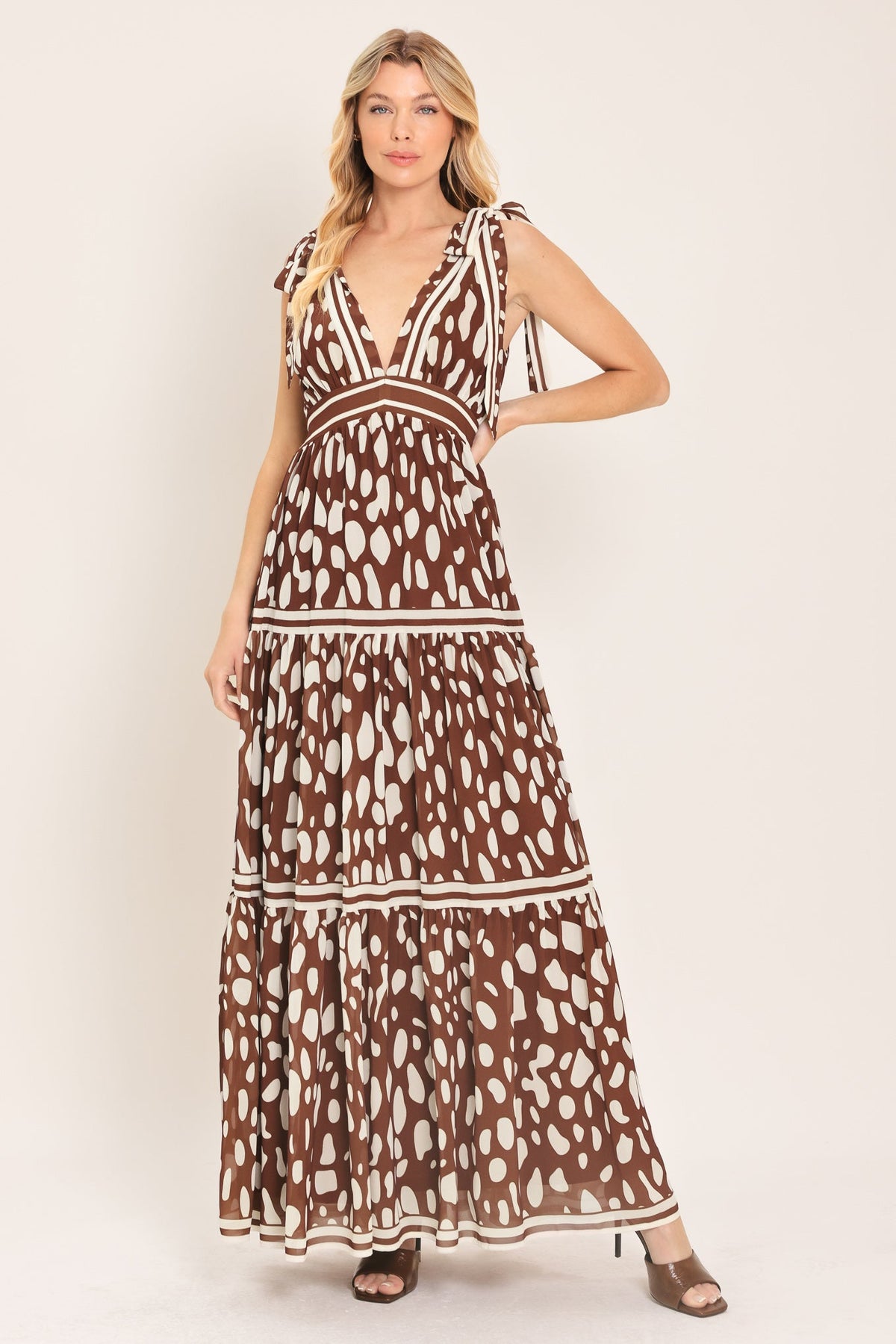 Woman wearing a brown and white patterned dress on a white background
