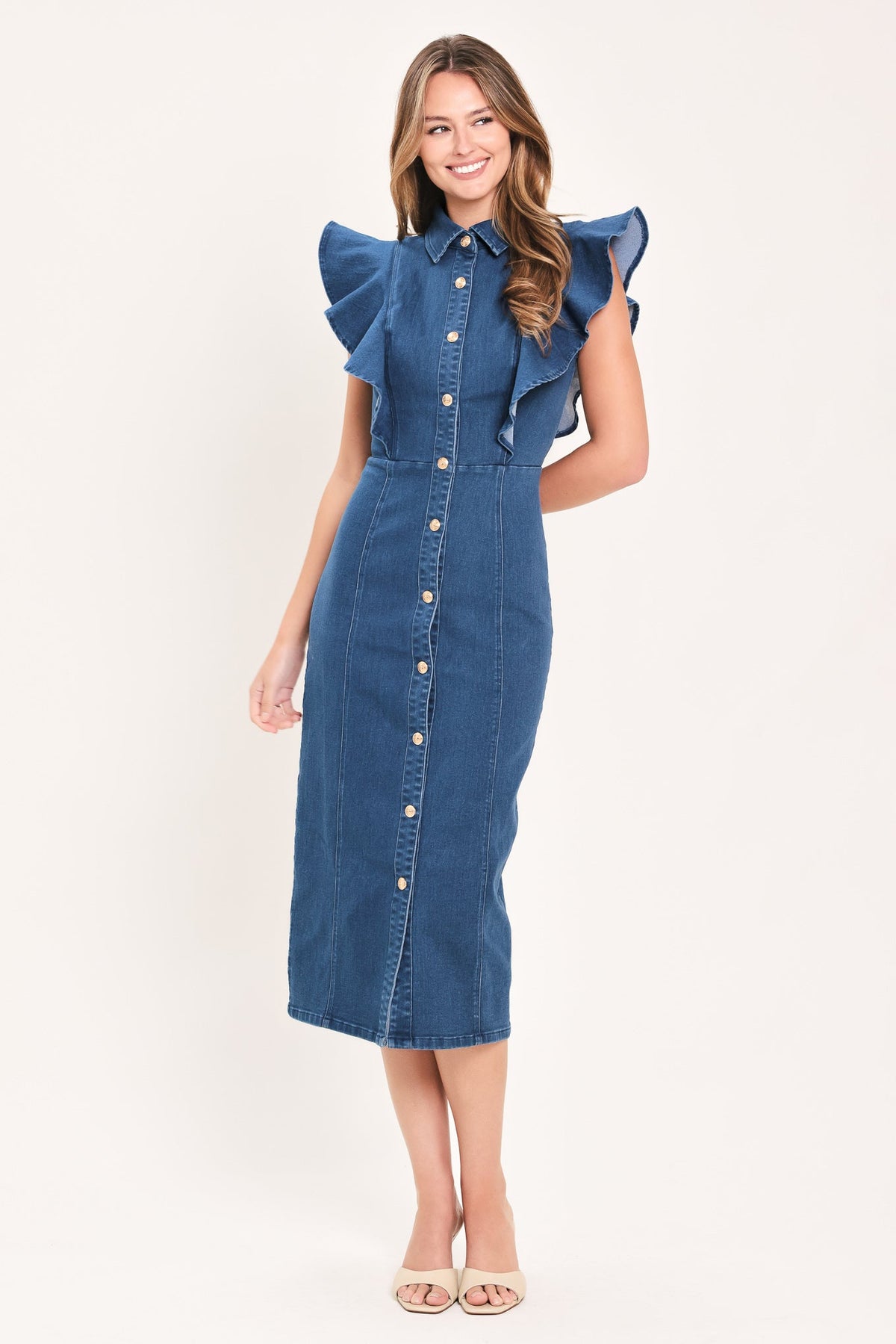 A woman modeling a blue denim midi dress with ruffled cap sleeves, a button-down front, and a pointed collar, photographed against a plain light background.
