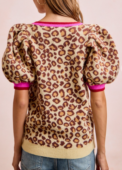 Leopard print sweater with pink trim worn by a person on a plain background