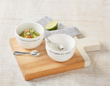 Two white bowls with silver spoons on a wooden cutting board with a light background