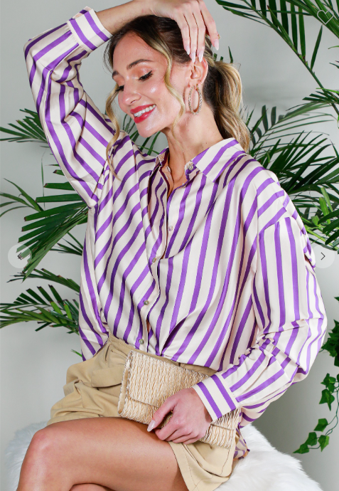 Woman wearing a purple and white striped shirt with plants in the background
