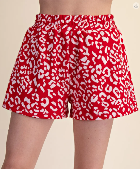 Red shorts with white leopard print pattern on a beige background