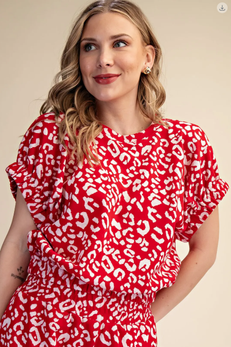 Woman wearing a red dress with white patterns against a beige background