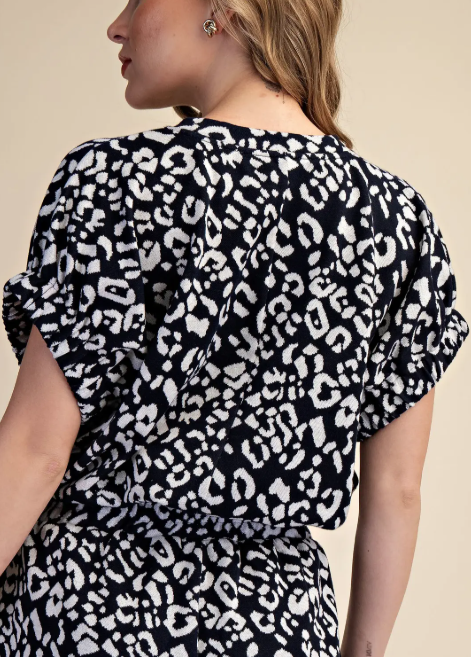Person wearing a black and white leopard print dress against a beige background