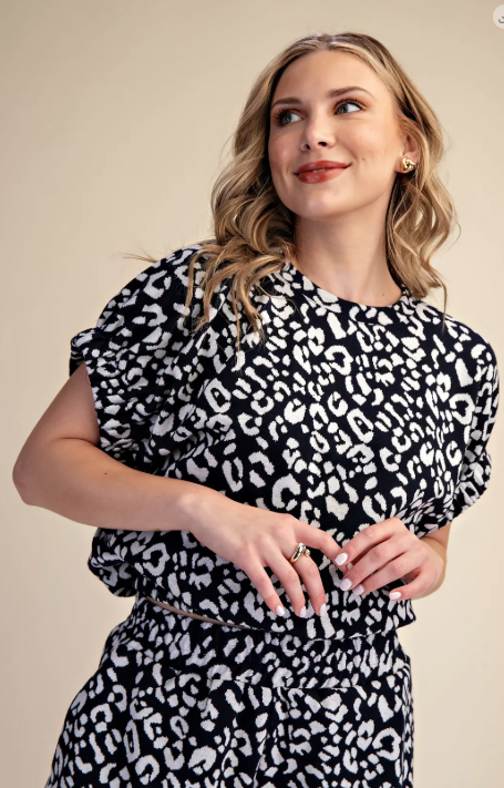 Woman wearing a black and white leopard print dress against a beige background