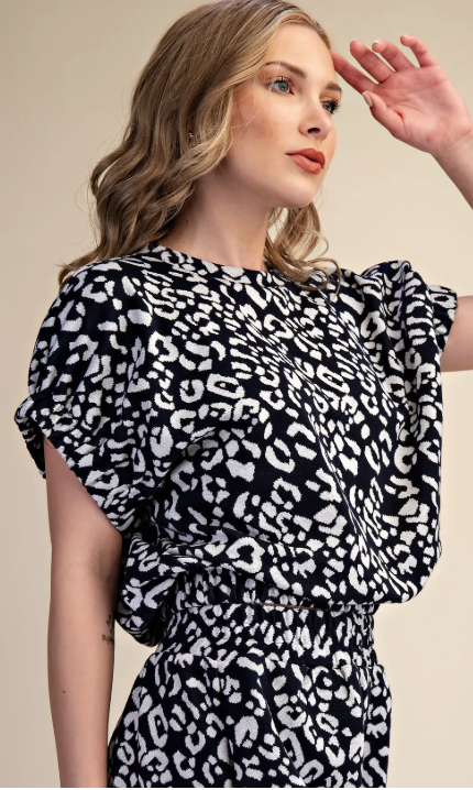 Woman wearing a black and white leopard print dress against a beige background