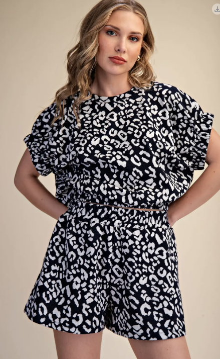 Woman wearing a black and white leopard print romper on a beige background