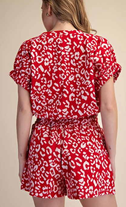 Person wearing a red and white leopard print outfit on a beige background