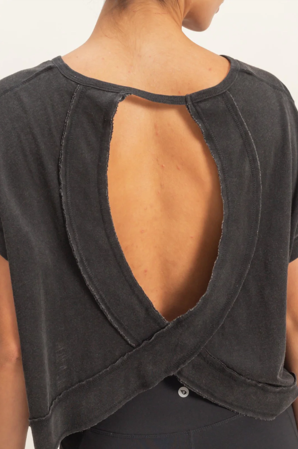 Black open-back top worn by a person on a neutral background
