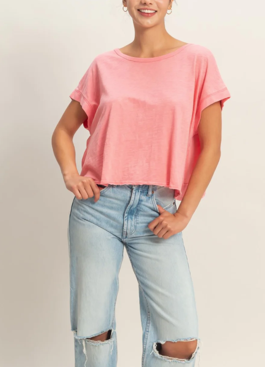 Person wearing a pink t-shirt and light blue jeans on a plain background