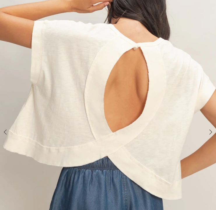 Woman wearing a white blouse with cut-out design on a plain background