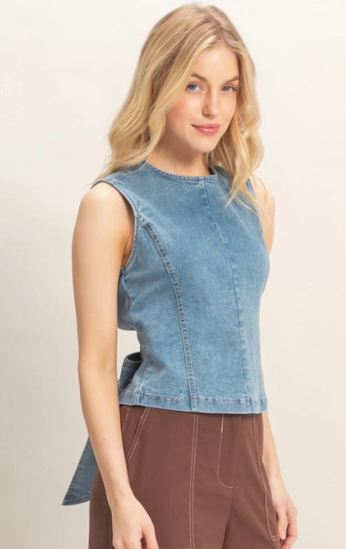 Woman wearing a sleeveless denim top with a beige background