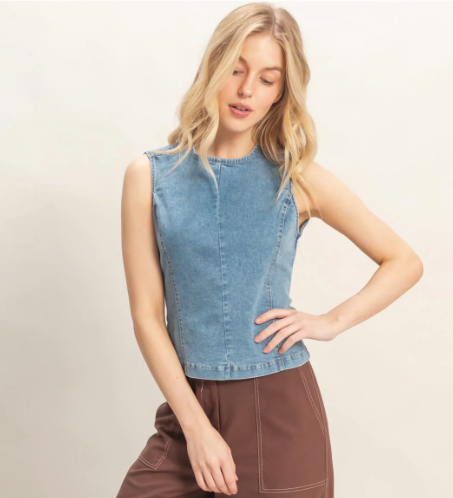 Woman wearing a denim sleeveless top against a plain background