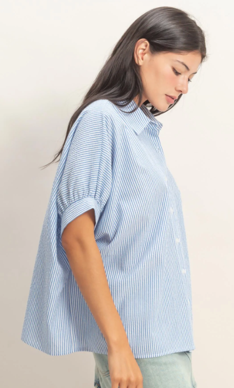Woman wearing a light blue striped shirt against a plain background