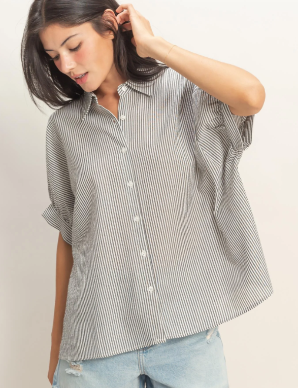 Woman wearing a striped shirt and jeans against a plain background
