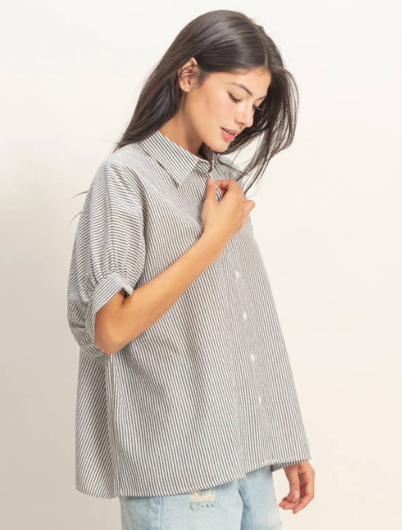Woman wearing a striped shirt and jeans on a plain background