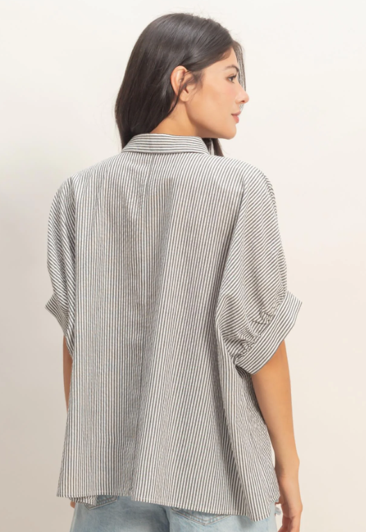Woman wearing a striped shirt from the back on a beige background