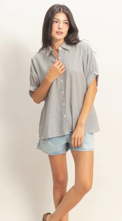 Woman wearing a striped shirt and denim shorts on a plain background