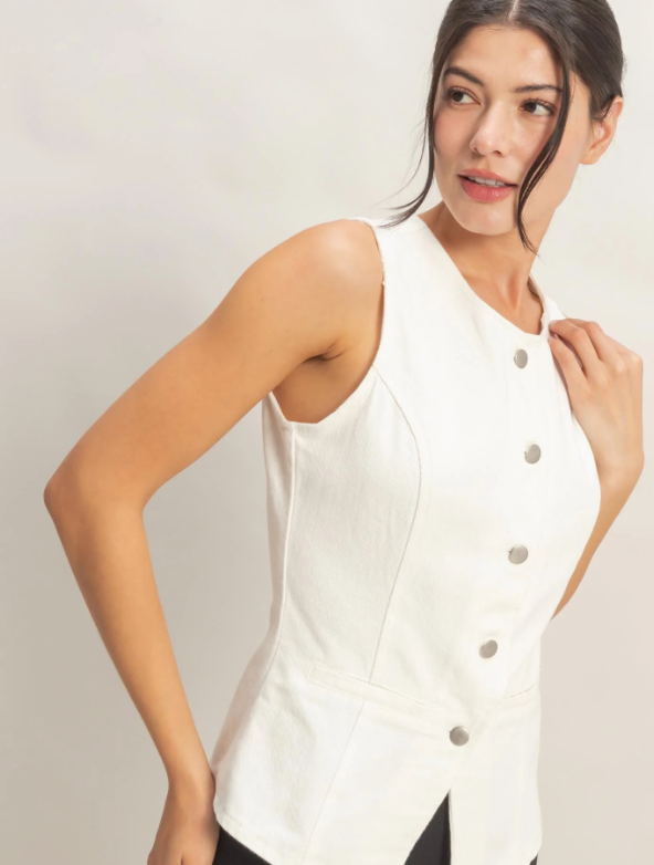 Woman wearing a white sleeveless button-up top against a plain background