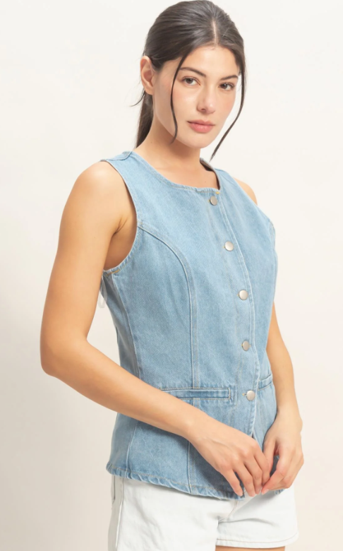 Woman wearing a light blue denim vest on a white background