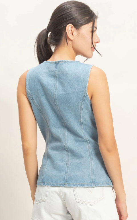 Woman wearing a light blue denim vest on a plain background