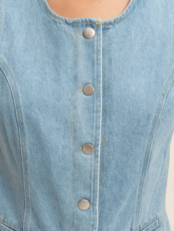 Close-up of a light blue denim jacket with button details.