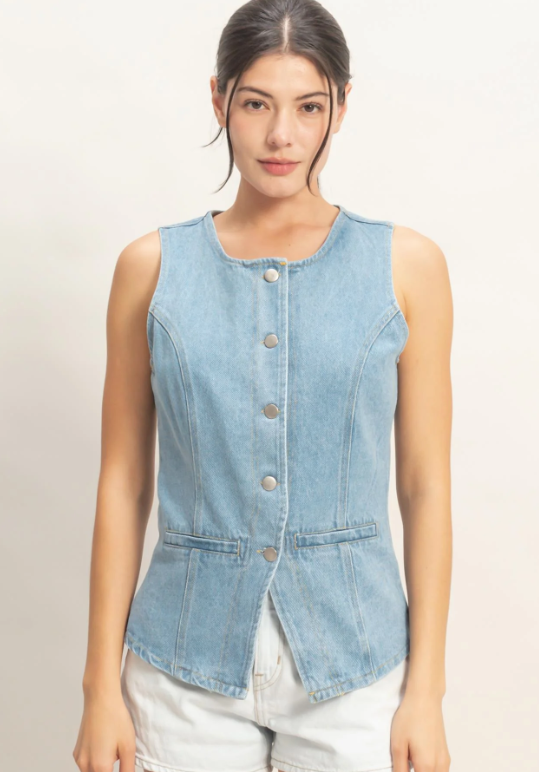 Woman wearing a light blue denim vest on a plain background