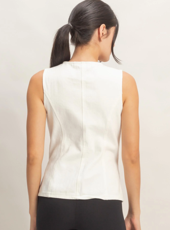 Woman wearing a white sleeveless top against a plain background