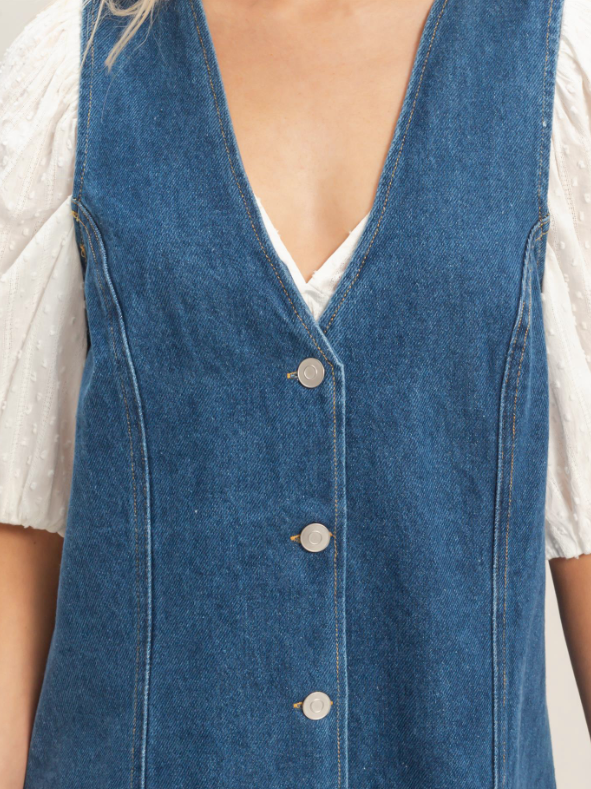 Blue denim vest worn over a white shirt on a neutral background